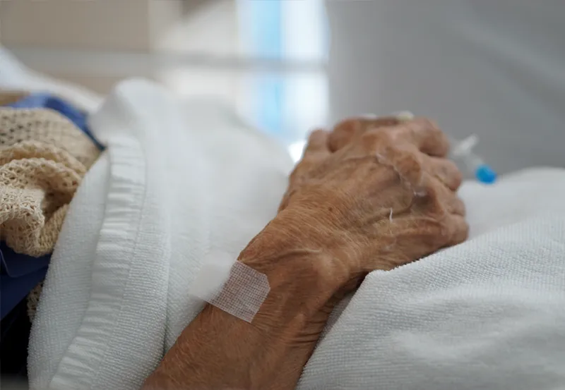 The hand of an elderly looking individual in a medical setting.