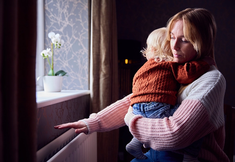 A female presenting individual holding their child.