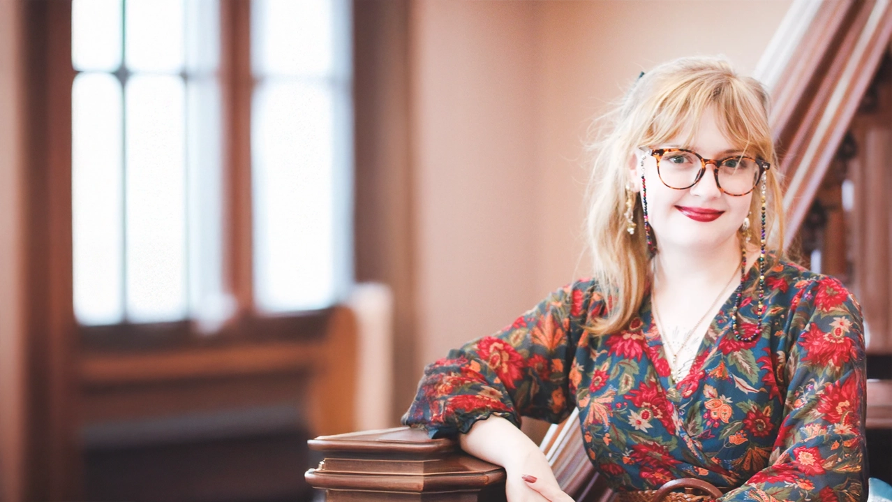 A female presenting individual walking down a city sidewalk.