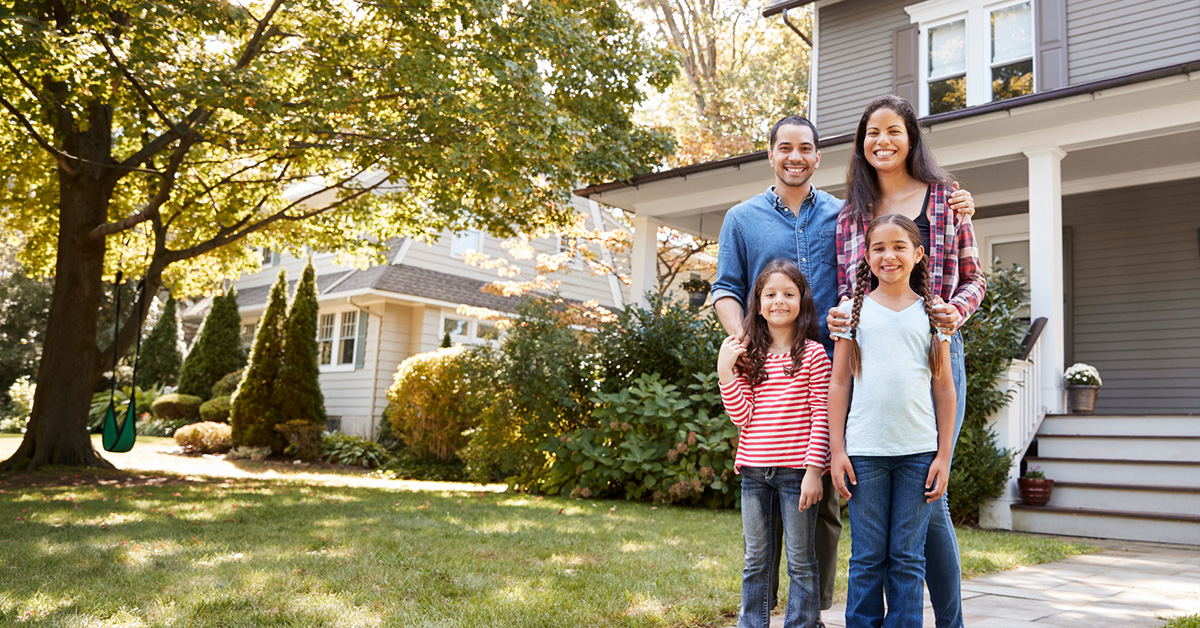 A family of four in the suburbs in front of what might be their house.